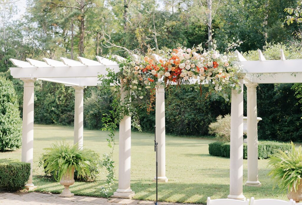 Pergola design at Historic Jasmine in Providence Forge, VA. Whimsical pergola design. Fall wedding flowers on a pergola. Orange and white flowers.