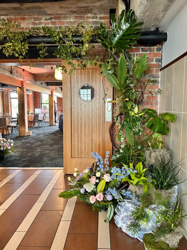 Overhead wedding ceremony entryway with plants and flowers. Large foliages. Reception at The Boathouse at Rockett's landing.